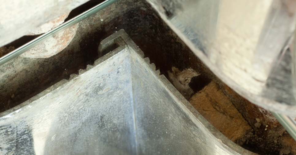 Hlavní obytný prostor (2. NP); spojení segmentů opláštění ocelových nosných sloupů; vlevo nahoře 	hlava nýtu, vpravo distanční dřevěný špalík s fragmentem původního linolea značky DLW, 2010, foto: David Židlický